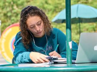 Student working on a laptop outside on a table at Stony Brook University