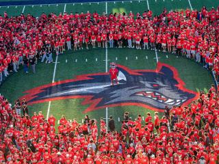 birds eye view of new students wearing red shirts standing in a circle on the field with the seawolf logo in the center.