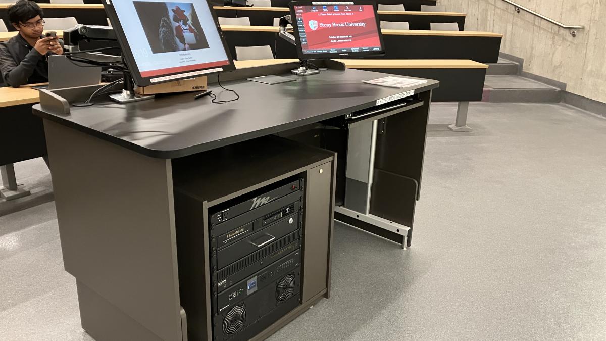 Lectern with two screens in front of a classroom