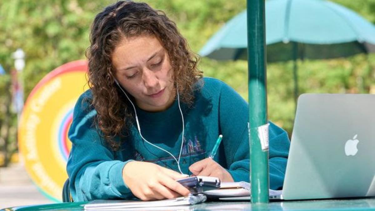 Student working on a laptop outside on a table at Stony Brook University