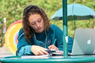 Student working on a laptop outside on a table at Stony Brook University