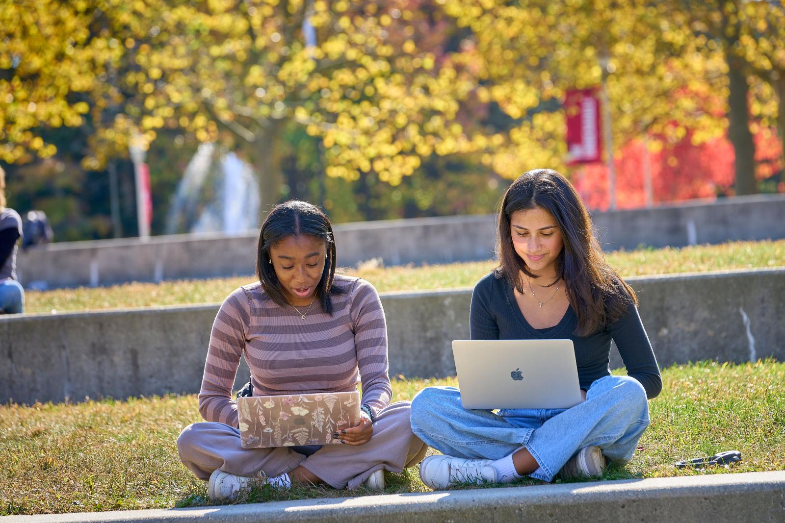 students on laptops with fall background